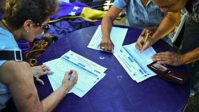 Los venezolanos firman un formulario durante la manifestación de la oposición. Foto: AFP/Ronaldo Schemidt