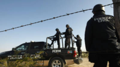 Mexican police stand guard in the site where the bodies of the members of the musical Band Kombo Kolombia were found, in Hidalgo municipality, New Leon state, Mexico on January 28, 2013. At least five corpses have been located in Hidalgo municipality in the north of Mexico, in the same place where last Friday there was brought the disappearance of 20 members of the musical group Kombo Kolombia, they informed this Monday local authorities. In accordance with safety sources of the New Leon State, military men and state police officers located on Sunday night the corpses, which were half-naked, with traces of torture and bullet wounds. AFP PHOTO/JULIO CESAR AGUILAR