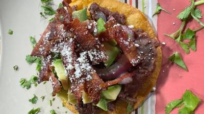 Este plato tradicional reinventado con ingredientes como tocino crujiente y cremoso aguacate, no solo expande los sabores, sino que también aporta una textura y riqueza adicionales.