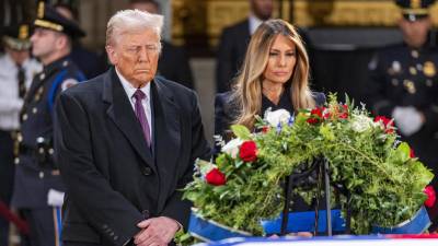 El presidente electo de Estados Unidos, Donald J. Trump, y Melania Trump se detienen ante el ataúd envuelto en la bandera del expresidente estadounidense Jimmy Carter.