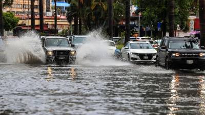Vehículos transitan por una calle inundada debido a las fuertes lluvias hoy, en el balneario de Acapulco.
