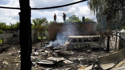 Dos hombres apagan un fuego, tras un ataque de misiles rusos hoy, en Chuhuiv (Ucrania).