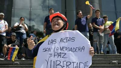 Una mujer sostiene un cartel que dice en español “Las actas de votación son la verdadera paz y libertad” durante una manifestación convocada por el candidato presidencial Edmundo González Urrutia
