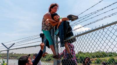 Un grupo de migrantes cruza una valla con alambrado en la frontera entre Texas y México./AFP Archivo.