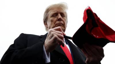 Presidente Donald Trump firma una gorra en una de las concetraciones políticas en su campaña electoral.