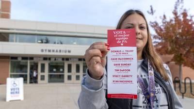 La voluntaria republicana Jackie Rivera, enseña un folleto con los nombres de todos los candidatos republicanos a la entrada de un centro de votación.