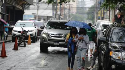 Jóvenes hondureñas caminan bajo la lluvia en una calle de San Pedro Sula | Fotografía de archivo