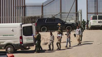 Migrantes detenidos son llevados por miembros de la Patrulla Fronteriza estadounidense a un vehículo, junto al muro fronterizo en El Paso, Texas (EE.UU).