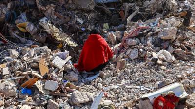 Una mujer sentada sobre los escombros de su casa espera los cuerpos de sus familiares en el lugar de los edificios derrumbados tras un fuerte terremoto, en Hatay, Turquía, el 15 de febrero de 2023.