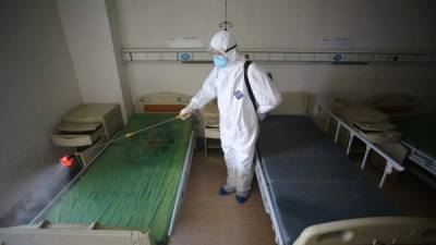 Un hombre se protege con un traje mientras limpia una camilla de un paciente con coronavirus. Fotos: AFP