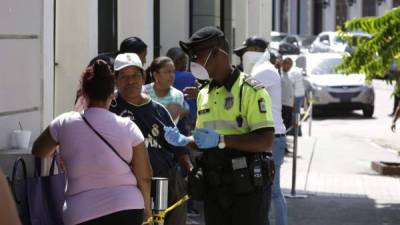 Un policía controla la fila de decenas de personas para comprar billetes de lotería, acción que desafía las medidas de seguridad y no aglomeración, este lunes, en Ciudad de Panamá (Panamá). EFE/Carlos Lemos