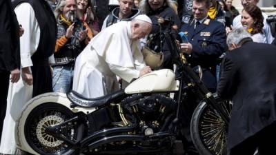 El papa Francisco firma en el depósito de una Harley Davidson mientras saluda a miembros de la asociación de motociclistas 'Moteros de Jesús' durante la audiencia general de los miércoles en la plaza de San Pedro en el Vaticano. EFE