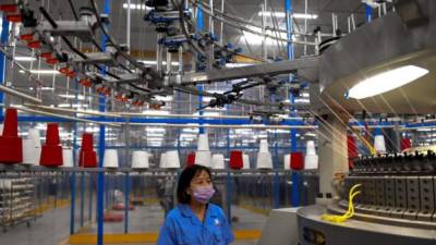 Una trabajadora monitorea una máquina de tejidos en una fábrica cerca de Shanghai.