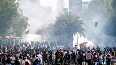 Cientos de personas protestan en la Plaza Italia este domingo durante una nueva jornada de manifestaciones en Santiago (Chile). El general de división del Ejército chileno Javier Iturriaga, responsable de la seguridad durante el estado de emergencia en la capital del país, ordenó este domingo un nuevo toque de queda 'para proteger la vida de todos' ante el agravamiento de los disturbios, que han dejado tres muertos. EFE/Esteban Garay.