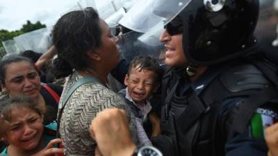 Una madre sostiene a un bebé que llora mientras toda la caravana lucha por cruzar una de las barreras en el puente fronterizo Guatemala-México en Ciudad Hidalgo, estado de Chiapas.
