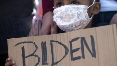 Dareli Matamoros, una niña de Honduras, sostiene un cartel pidiendo al presidente Biden que la deje entrar durante una manifestación de migrantes en el puerto de cruce de San Ysidro en Tijuana, Baja California. AFP