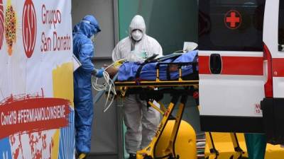 Medical workers stretch a patient from an Italian Red Cross ambulance into an intensive care unit set up in a sports center outside the San Raffaele hospital in Milan, on March 23, 2020 during the COVID-19 new coronavirus pandemic. , (Photo by Miguel MEDINA / AFP)