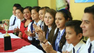 Los escolares en compañía de su maestra asesora festejan el logro en su centro educativo con la copa de campeones en la mesa. Fotos: Amílcar Izaguirre