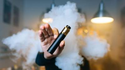 beard man show vaping device on his outstretched hand