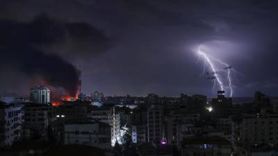 Caen relámpagos mientras se eleva el humo tras el bombardeo israelí de la ciudad de Gaza el 9 de octubre de 2023.