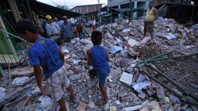 Personas afectadas recorren entre los escombros de las casas caídas en la ciudad de Manta.