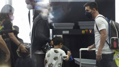 Barcelona's departing Argentinian forward Lionel Messi (R) arrives with his family to board a plane at El Prat airport in Barcelona on August 10, 2021. - France is waiting impatiently for Lionel Messi with supporters gathering outside Paris Saint-Germain's ground hoping to see the Argentine who is expected to join the Qatar-owned club after his exit from Barcelona. (Photo by Josep LAGO / AFP)