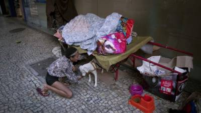 Una mujer sin techo juega con su perro en el barrio Lapa de Rio de Janeiro.