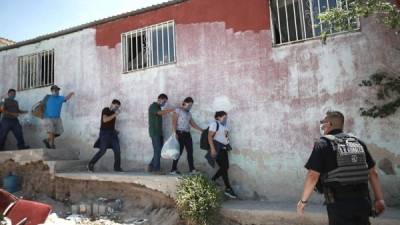 Migrantes que buscaban cruzar hacia Estados Unidos salen de una vivienda donde se encontraban escondidos tras ser arrestados por miembros de la Seguridad Pública, hoy, en Ciudad Juárez, estado de Chihuahua. (México). EFE/ Luis Torres