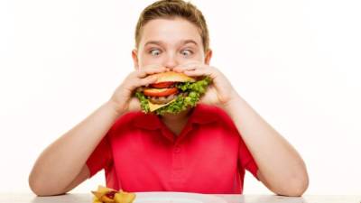 Foto referencial de un niño comiendo una hamburguesa.