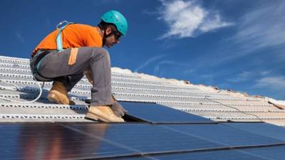 El objetivo es crear una plataforma económica completamente verde. Un trabajador instala paneles solares.
