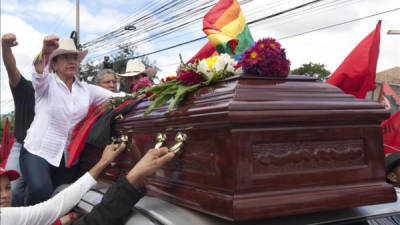 La candidata presidencial del Partido Libertad y Refundación (LIBRE) en las elecciones del pasado 24 de noviembre, Xiomara Castro (i), y su esposo, el expresidente derrocado Manuel Zelaya (c), saludan a simpatizantes este 1 de diciembre de 2013, en Tegucigalpa (Honduras), junto al ataúd con los restos del activista José Antonio Ardón, asesinado el pasado sábado. EFE