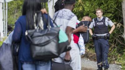 Un oficial de EUA, en Champlain, advierte a un grupo haitianos sobre no cruzar ilegalmente la frontera hacia Canadá.