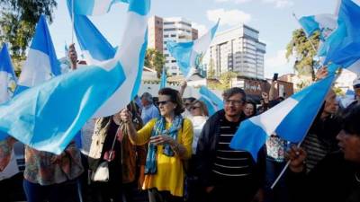 Decenas de personas acuden con banderas nacionales a la sede de la Comisión Internacional Contra la Impunidad en Guatemala (Cicig) para celebrar la decisión que hizo hoy la entidad de pedirle a su personal que abandone el país 'hasta nuevo aviso'. EFE/