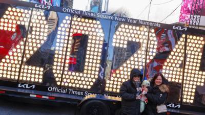 Dos personas posan para fotos frente a los números de siete pies de altura '2024', que se colocarán en la cima de One Times Square para la celebración del Año Nuevo, hoy, en Nueva York.