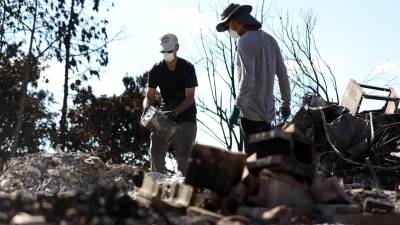 Brook Cretton y Spencer Kim revisan las ruinas de uno de los hogares destruidos en Lahaina.