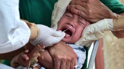 Un pequeño llora mientras toman una muestra para analizar el nuevo coronavirus. Foto: AFP