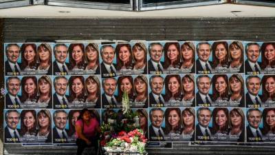 A woman sells flowers under a political propaganda of Argentina's President and presidential candidate of Juntos por el Cambio party Mauricio Macri (R) and presidential candidate Alberto Fernandez (L) of the Frente de Todos party, in Buenos Aires, on October 25, 2019. (Photo by RONALDO SCHEMIDT / AFP)