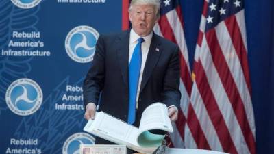 El presidente estadounidense, Donald Trump, hojea un memorando sobre el impacto medioambiental de la construcción de una carretera antes de pronunciar un discurso sobre futuras inversiones en infraestructuras de transporte en el departamento de Transporte en Washington (Estados Unidos), este 9 de junio del 2017. EFE