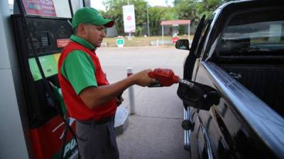 Un bombero llena el tanque de combustible de un auto.