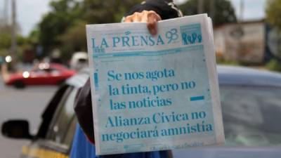 Un vendedor ofrece un ejemplar del diario La Prensa, con su portada completamente en azul, en una calle de Managua.