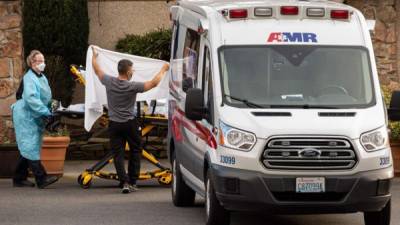 Los trabajadores de la salud transportan a un paciente en camilla a una ambulancia en el Life Care Center de Kirkland en Kirkland, Washington.