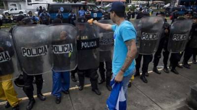 Un joven fue registrado este sábado al dejarle una flor a uno de policía antidisturbios, durante un nuevo plantón antigubernamental, en Managua (Nicaragua). EFE/Jorge Torres