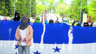 Jóvenes con los rostros cubiertos mantienen tomada la Unah. Fotos: Andro Rodríguez