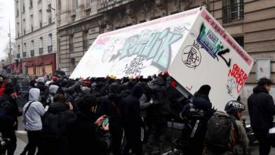 Los manifestantes volcaron hoy un contenedor durante una manifestación contra la revisión de las pensiones, en París como parte de una huelga a nivel nacional.