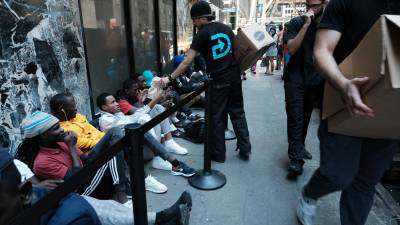 Un grupo de migrantes recibe alimentos de voluntarios mientras esperan para solicitar albergue en Nueva York.