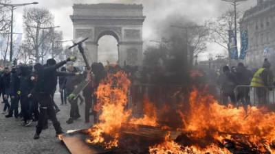 Los chalecos amarillos se enfrentan a las fuerzas policiales durante los enfrentamientos en los Campos Elíseos hoy en París, Francia. EFE