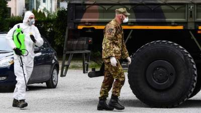 Dos hombres en Italia se cubren con una mascarilla para protegerse del coronavirus. Foto: AFP