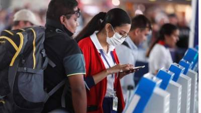 Una empleada del aeropuerto Arturo Merino Benítez en Santiago (Chile), asiste a un pasajero portando una mascarilla para evitar el contagio del coronavirus este miércoles, después que ayer se confirmaran los dos primeros casos en el sur del país. EFE/Alberto Valdes