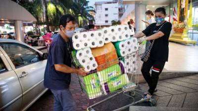 Una pareja empuja un carro de supermercado cargado de papel higiénico. Fotos: AFP