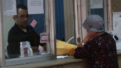 Una mujer de la tercera edad es atendida por personal del correo.